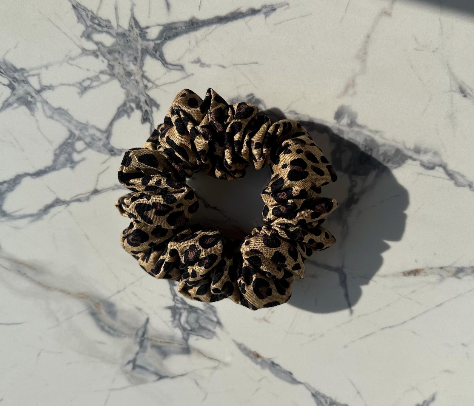 Leopárdmintás textil scrunchie márvány háttér előtt